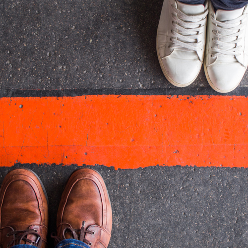 Man And Woman Standing Opposite Each Other On Either Side Of The Road, Divided By A Red Line