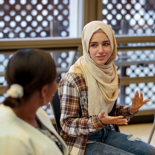 People sat together in a group with a women in a hijab talking 