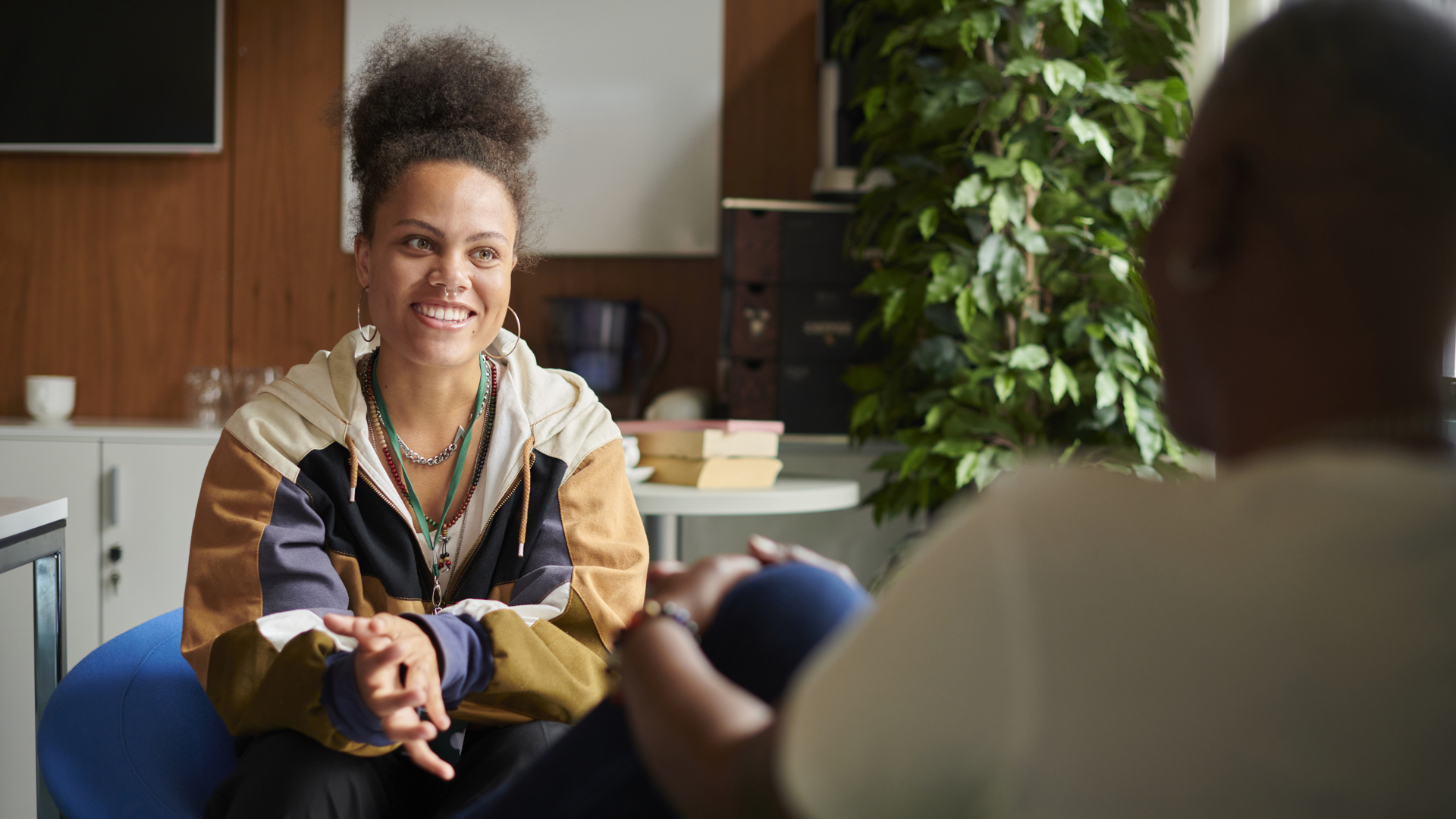 Young women sitting down and smiling and person sat across from her 