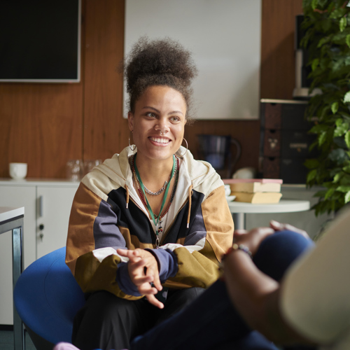 Young women sitting down and smiling and person sat across from her 